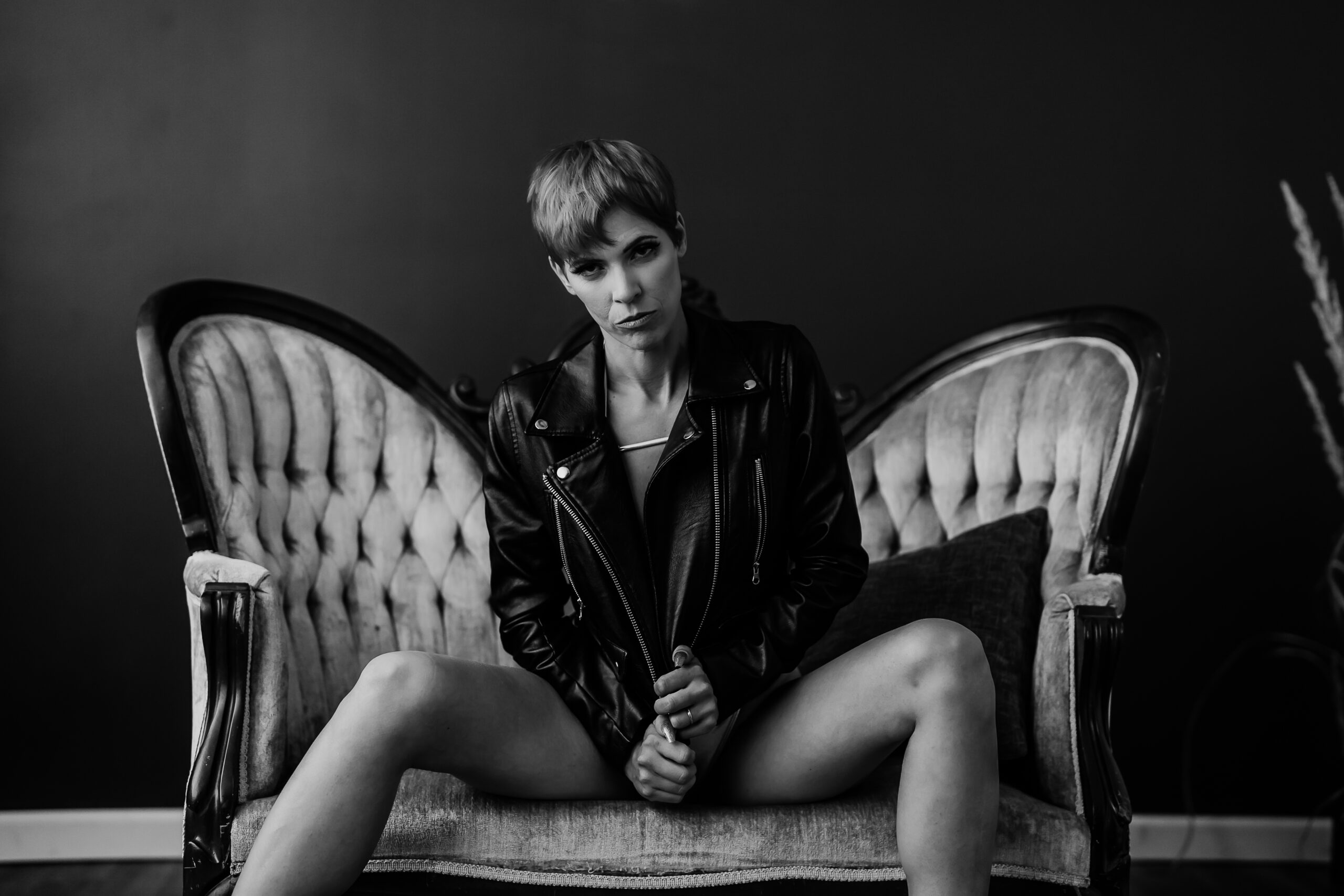 Gay woman on velvet couch wearing a motorcycle jacket. Picture by Katie O'Docharty, Denver Boudoir Photographer